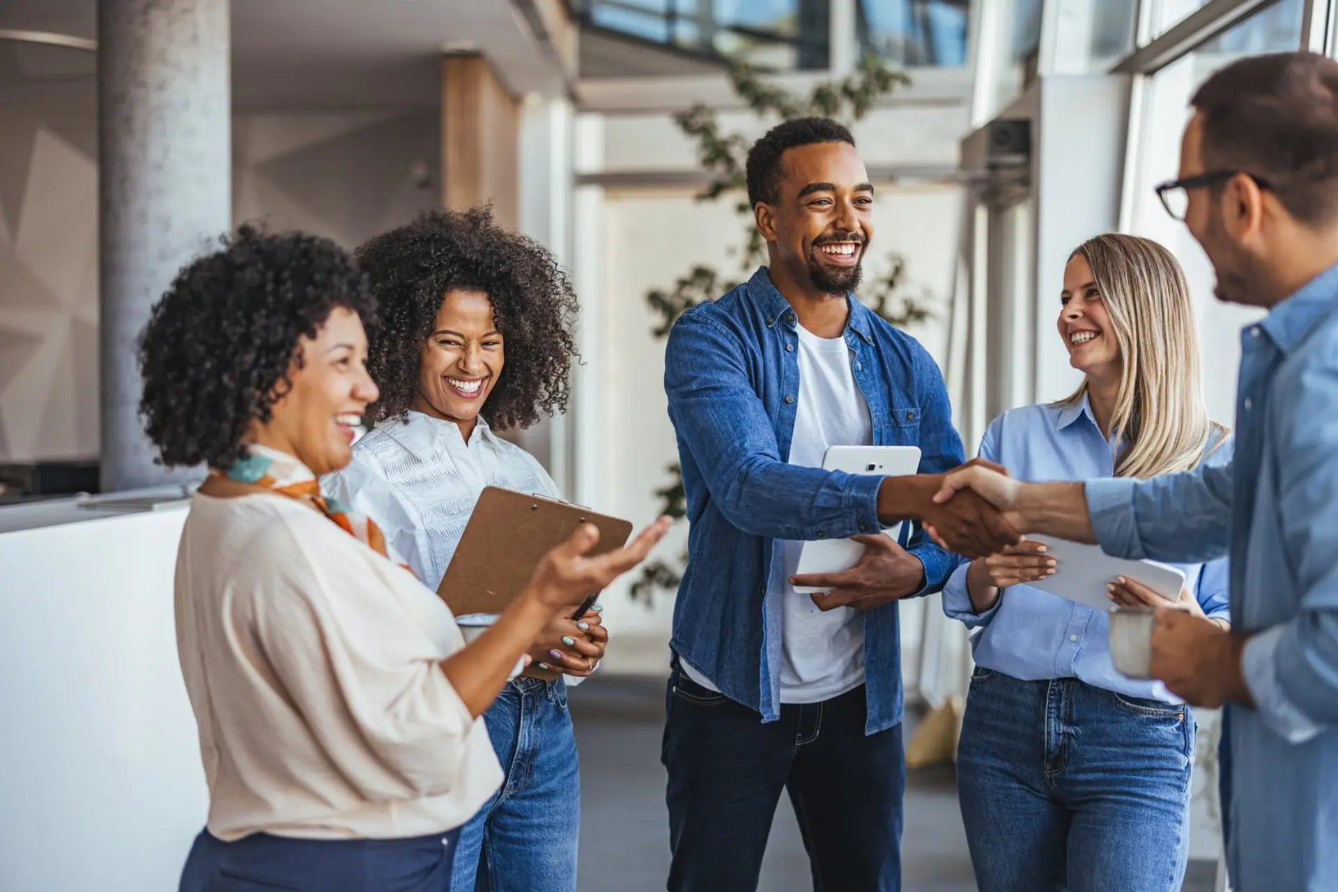 A diverse group of professionals smiling and shaking hands in a modern office environment