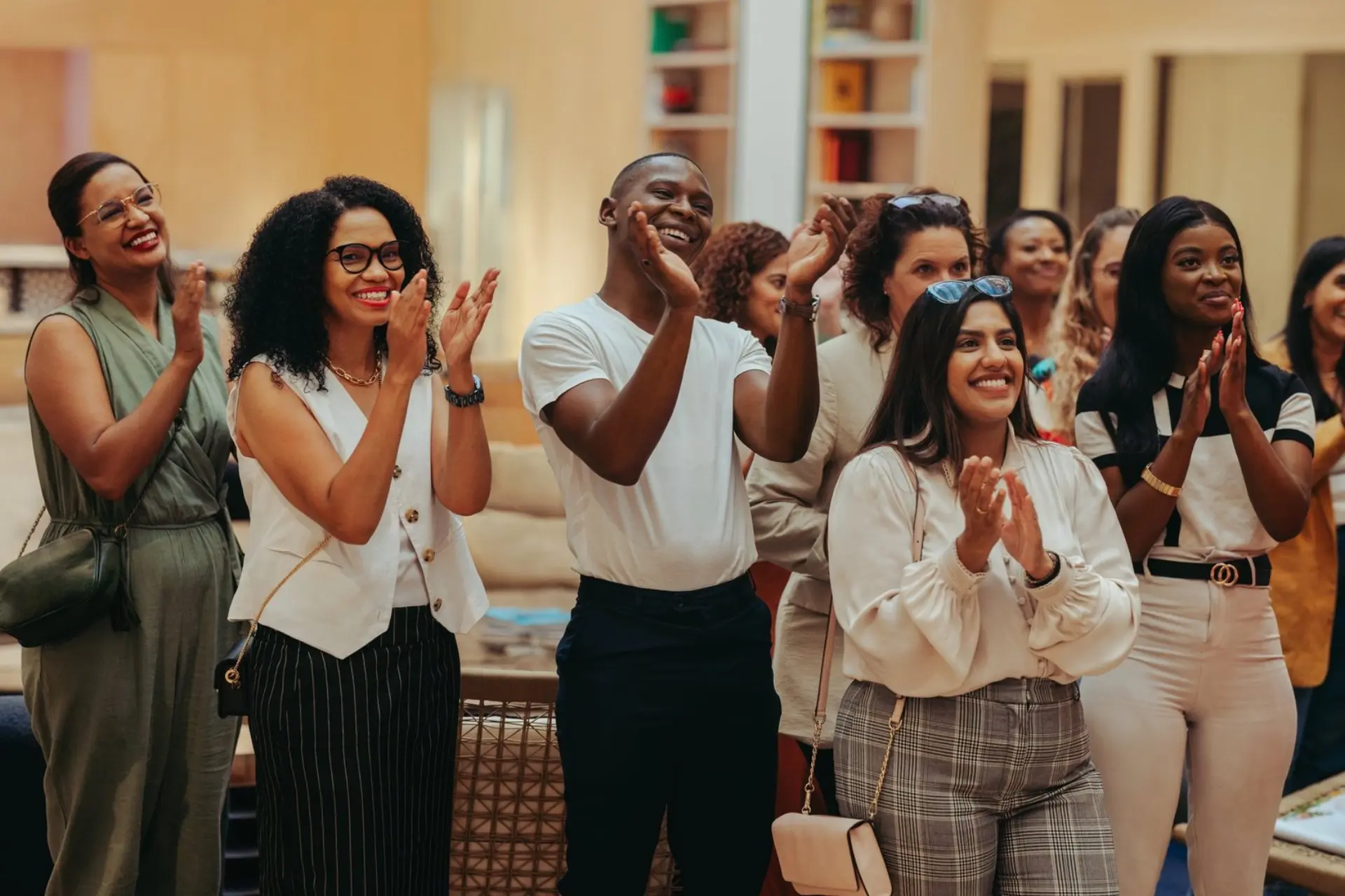 A diverse group of happy employees clapping and smiling in an office setting