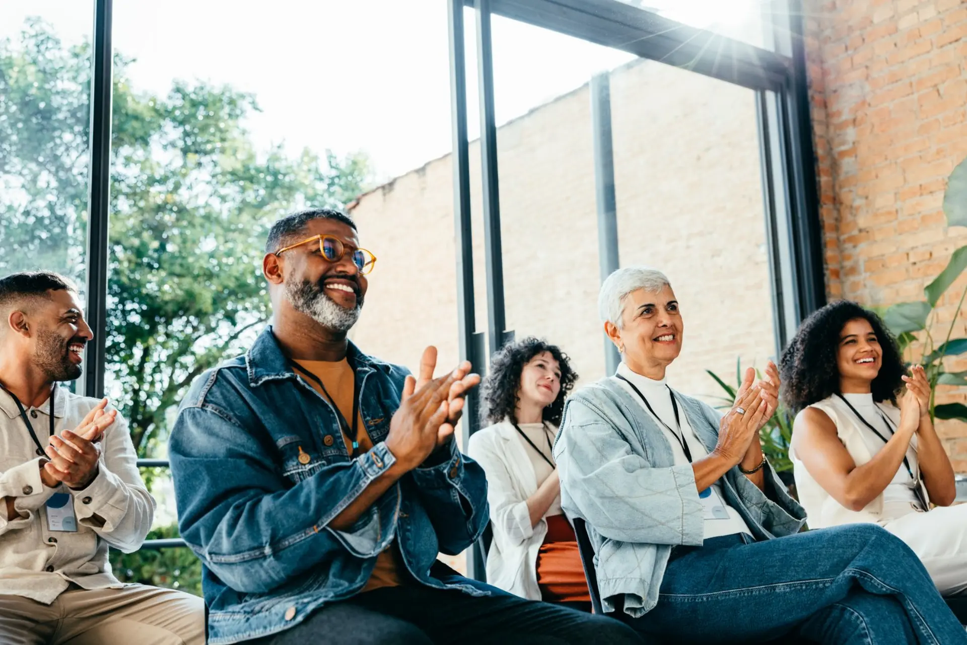 Diverse group of people attending a meeting, happily clapping and smiling