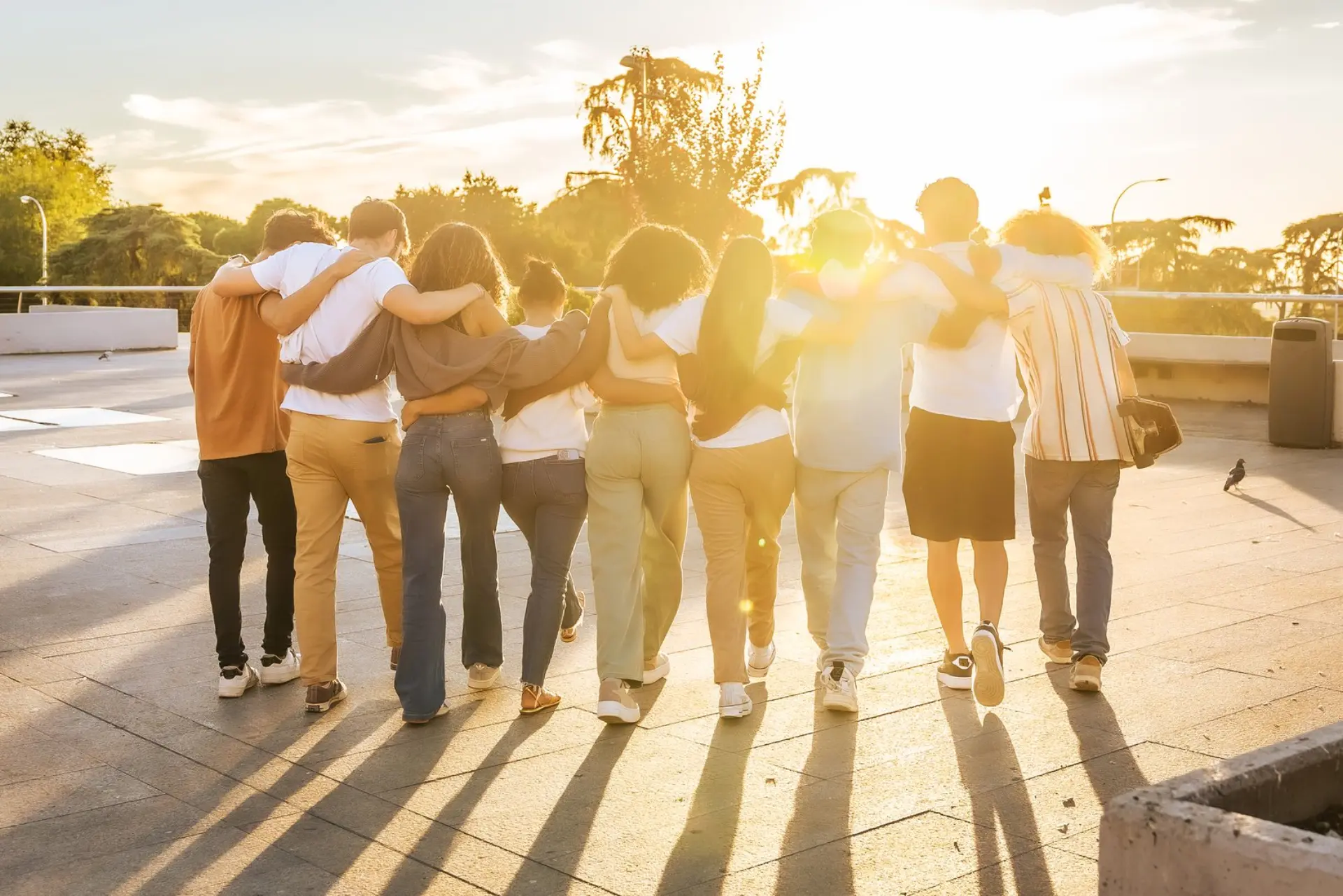 Students walking together with arms around each other, enjoying the sunset