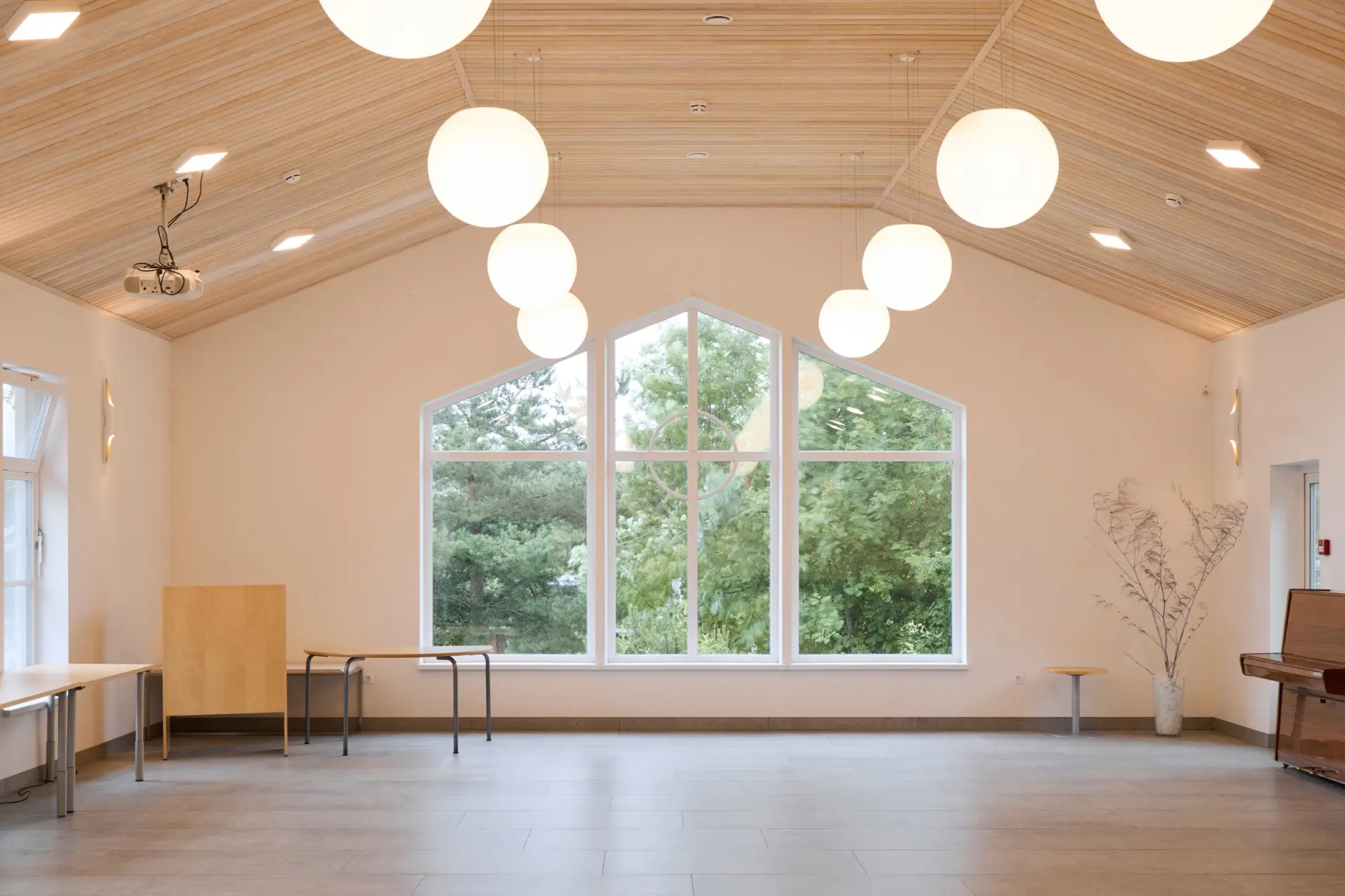 A modern community hall with large windows for natural light and elegant pendant lights